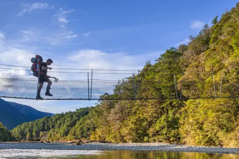 Thumbnail of Darryn Pegram crossing swingbridge over Travers River Nelson Lakes NP Nelson Photo Shaun Barnett