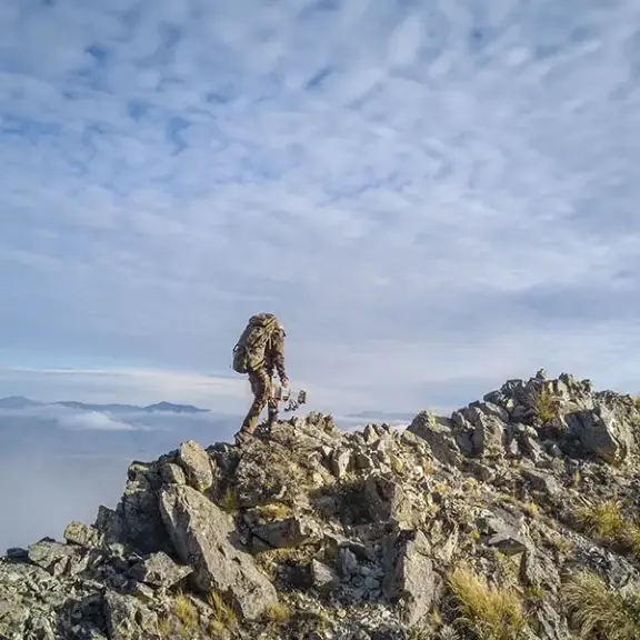 Bow hunter climbing ridge