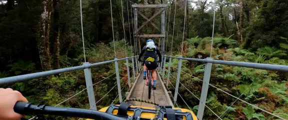 Mountainbikers crossing bridge on Paparoa Track