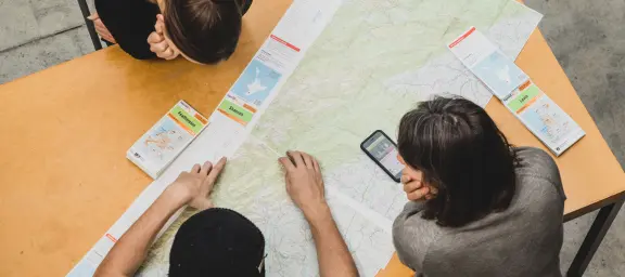 Group planning a trip using a printed map and Plan My Walk