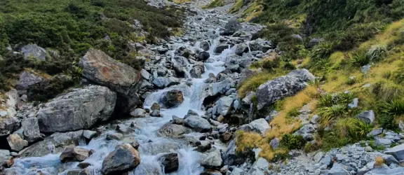 View of tramper hiking up a valley beside the West Branch of the Sabine River 