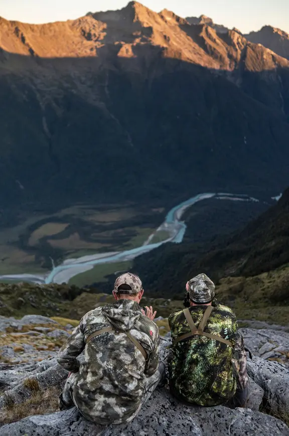 Hunters resting on rock overlooking valley